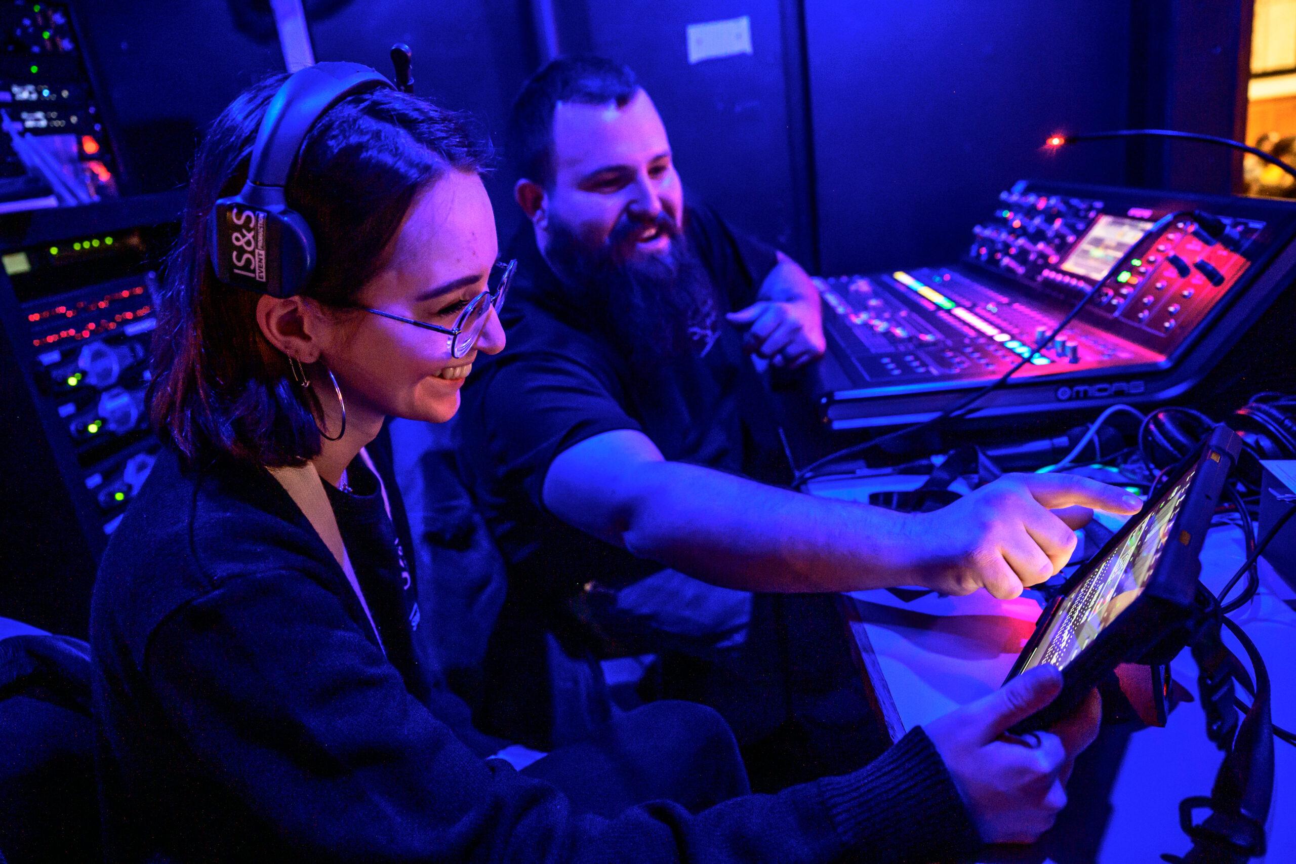Audio Visual student and staff member working in booth at a convocation